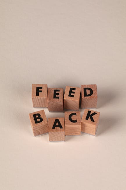 Wooden blocks forming the word 'Feedback' against a neutral beige background, conveying communication or review concept.