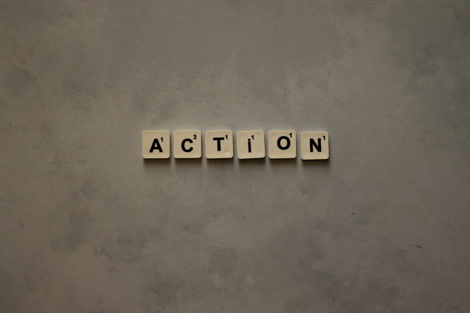 Scrabble tiles forming the word 'Action' on a textured gray surface, conveying motivation.