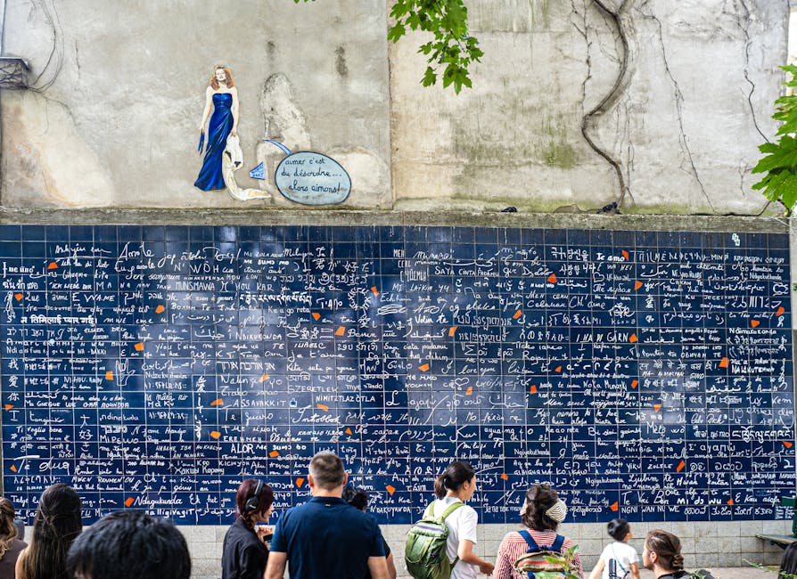 Visitors admire the iconic Wall of Love in Paris, featuring multiple languages and artistic elements.