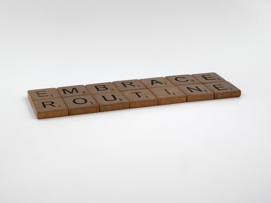 Wooden Scrabble tiles spelling 'Embrace Routine' on a minimalist white background, emphasizing typography.